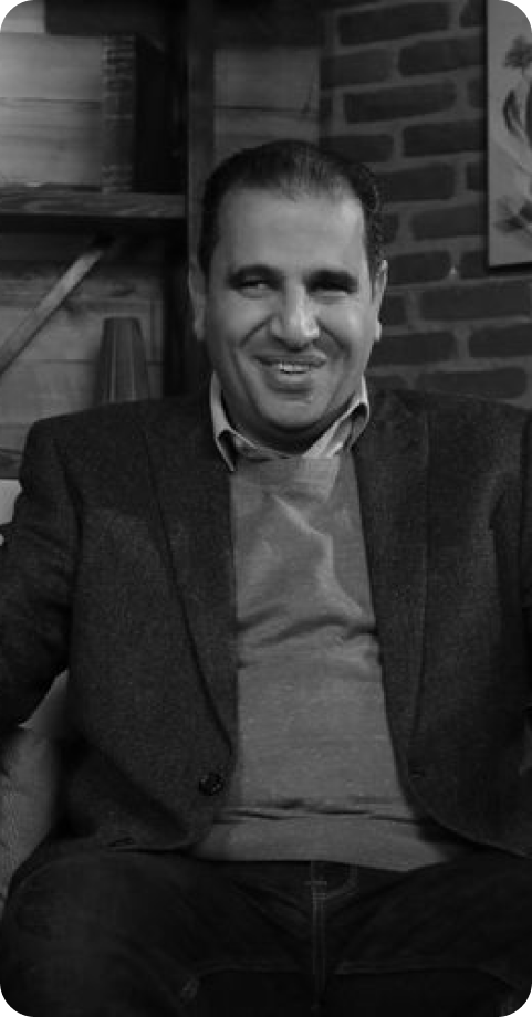 Mohamed Attia, the CEO and founder, sitting on a chair, smiling, in a cozy room with a brick wall and framed artwork in the background.