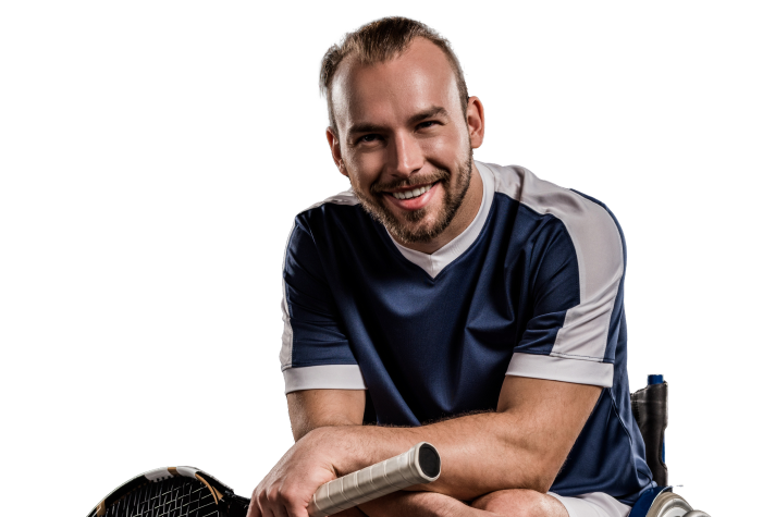 A smiling man in a sports uniform holding a tennis racket, sitting on a wheelchair.