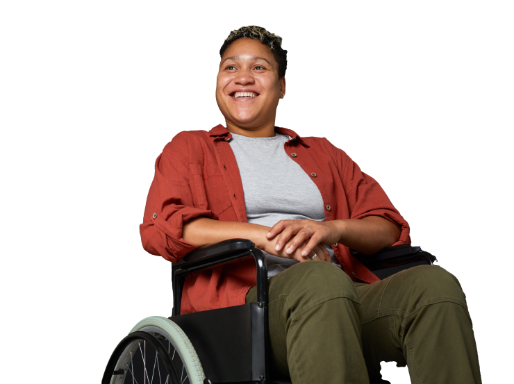 A smiling African woman in a wheelchair, wearing a red shirt over a gray T-shirt and olive green pants.