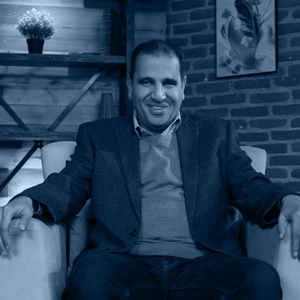 Dr. Mostafa Attia, CEO and founder, smiling while sitting in a cozy room with a brick wall and framed artwork.