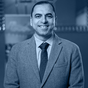 Dr. Ayman Tantawy, in a suit and tie, smiling confidently against a blurred background.