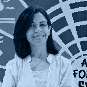 A woman smiles cheerfully for a photo, dressed in casual clothing.