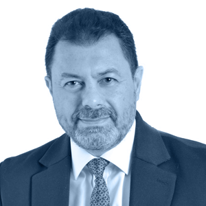 A man in a suit and tie poses confidently against a neutral background.