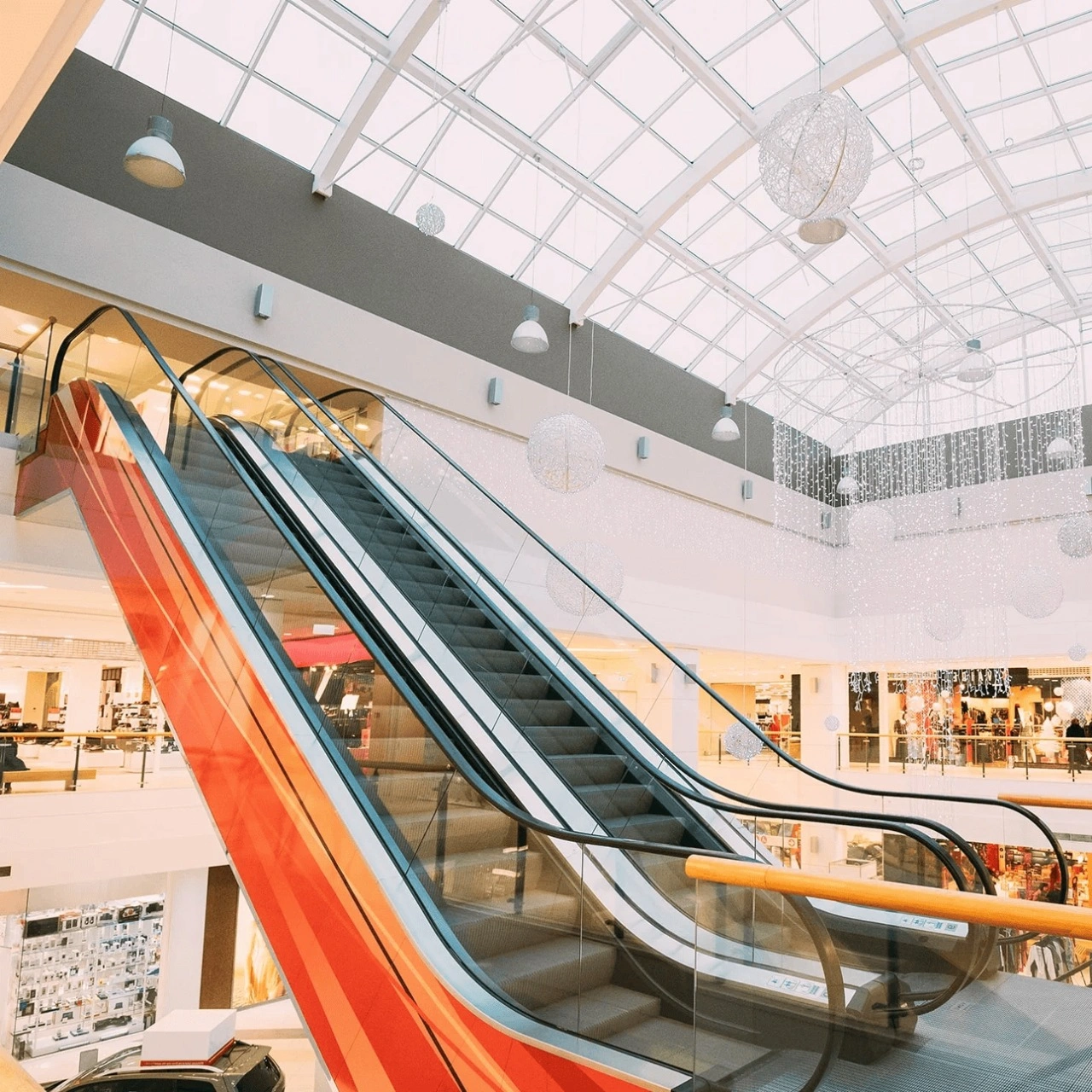 An escalator in a mall, showing the handrail and surrounding indoor environment.