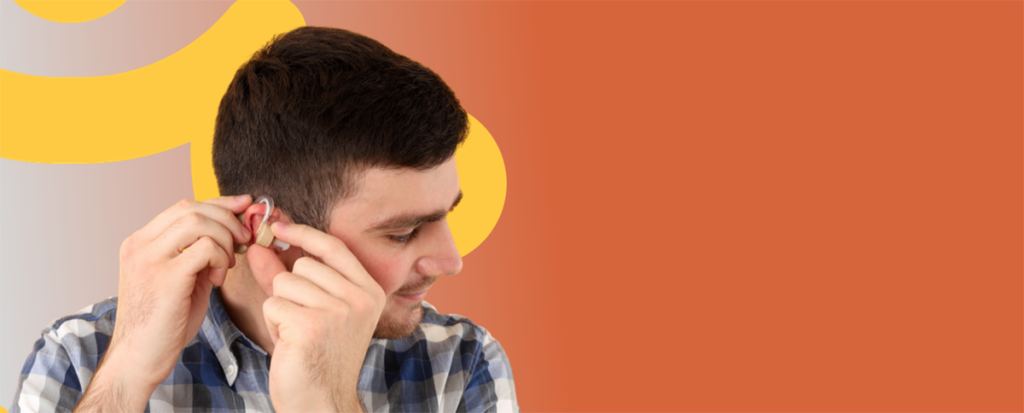 رجل يرتدي قميصًا منقوشًا يضبط سماعة الأذن الخاصة به، مبتسمًا، على خلفية برتقالية وصفراء.