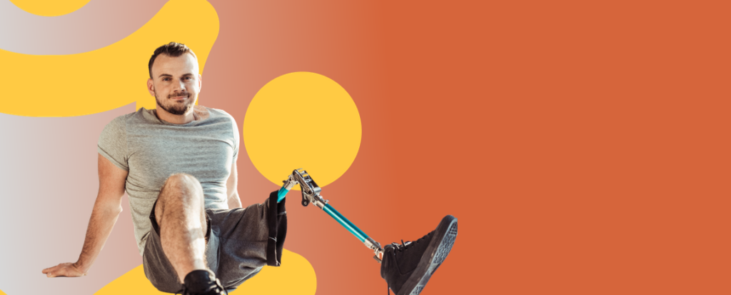 شخص يرتدي قميصًا رماديًا وشورت يجلس على الأرض، يستعرض ساقًا صناعية زرقاء، أمام خلفية برتقالية زاهية.